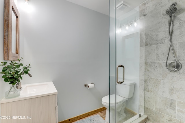 bathroom with toilet, baseboards, tiled shower, and vanity