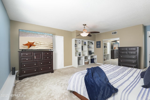 bedroom with a textured ceiling, light carpet, visible vents, baseboards, and a ceiling fan