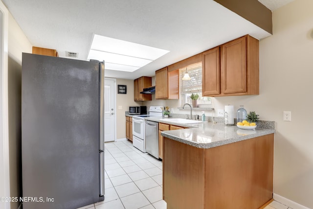 kitchen with visible vents, brown cabinets, a peninsula, stainless steel appliances, and a sink