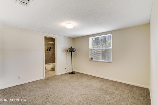 unfurnished bedroom featuring carpet floors, visible vents, a textured ceiling, ensuite bath, and baseboards