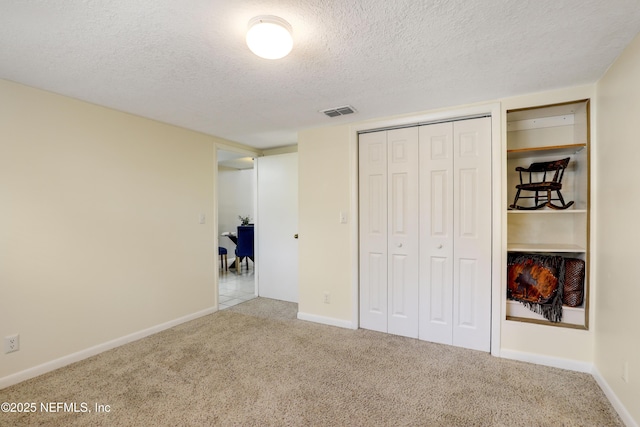 unfurnished bedroom with carpet floors, visible vents, baseboards, and a textured ceiling