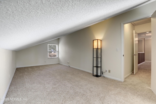 additional living space featuring a textured ceiling, carpet, lofted ceiling, and baseboards