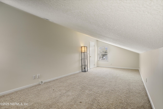 interior space with baseboards, vaulted ceiling, and a textured ceiling