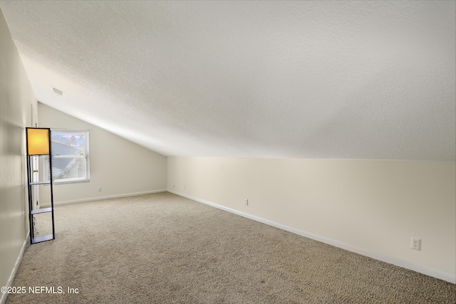 bonus room with a textured ceiling, lofted ceiling, carpet floors, visible vents, and baseboards