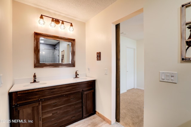 bathroom featuring a textured ceiling, double vanity, a sink, and baseboards