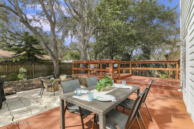 view of patio / terrace with a deck, outdoor dining space, and fence