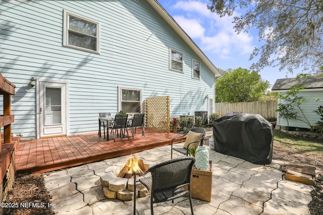 view of patio with an outdoor fire pit, area for grilling, fence, a deck, and outdoor dining space