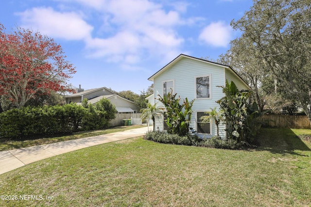 view of front facade with driveway, fence, and a front lawn