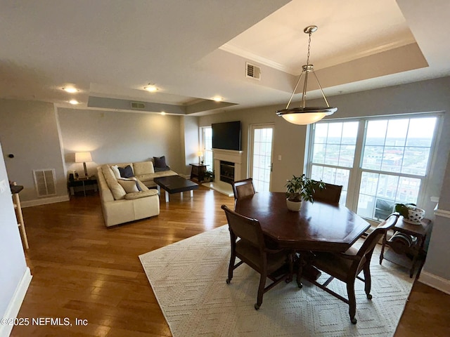 dining area with ornamental molding, a raised ceiling, and hardwood / wood-style floors