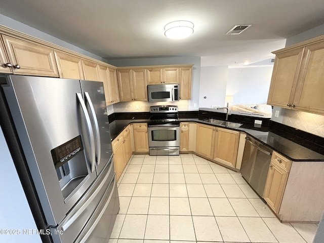 kitchen with sink, light tile patterned floors, appliances with stainless steel finishes, light brown cabinetry, and decorative backsplash