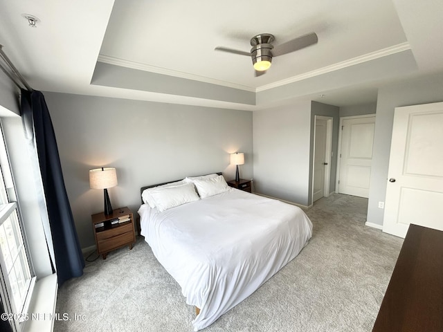 bedroom with ornamental molding, light colored carpet, and a raised ceiling