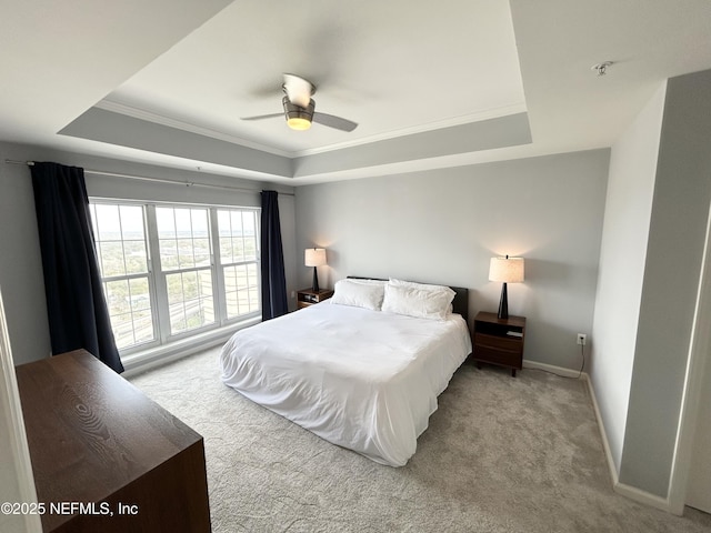 carpeted bedroom with a tray ceiling, ornamental molding, and ceiling fan
