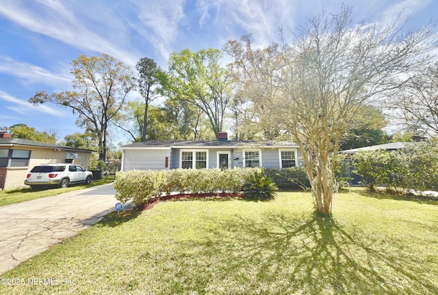 view of front of home with a chimney, concrete driveway, and a front lawn