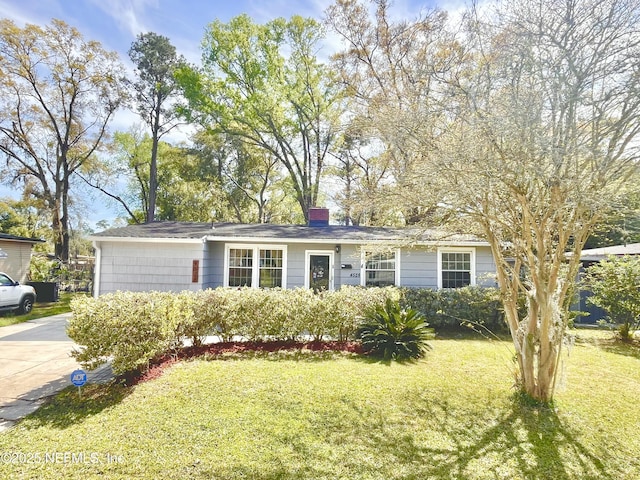 ranch-style house with concrete driveway, a chimney, and a front lawn