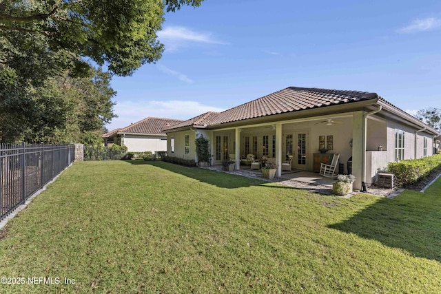 rear view of property with ceiling fan, a patio, and a lawn