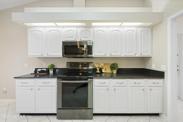 kitchen featuring vaulted ceiling, appliances with stainless steel finishes, and white cabinets