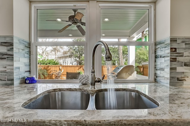 room details with ceiling fan, sink, and light stone countertops