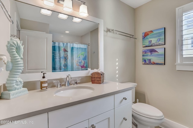 bathroom featuring toilet, vanity, and walk in shower