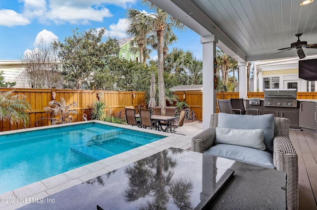 view of swimming pool with ceiling fan, grilling area, a patio area, and exterior kitchen