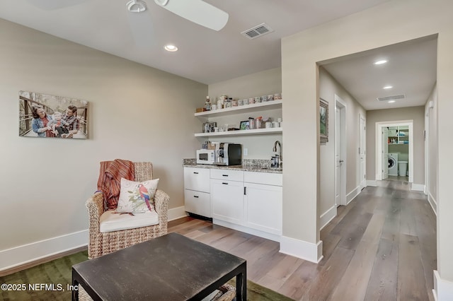 sitting room with ceiling fan, washing machine and clothes dryer, sink, and hardwood / wood-style floors