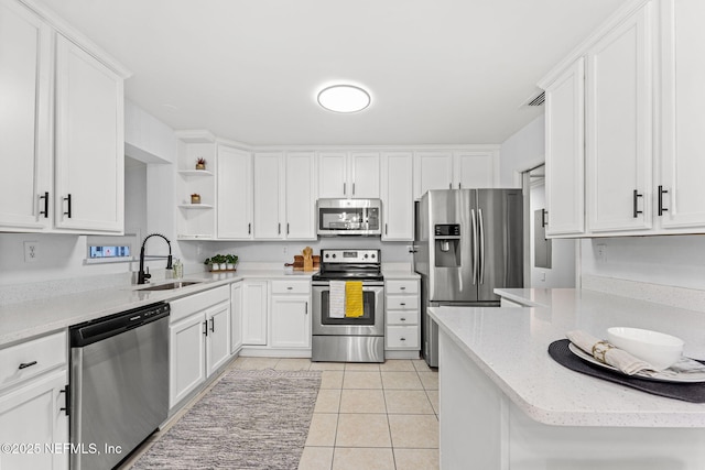 kitchen with light tile patterned flooring, sink, white cabinetry, kitchen peninsula, and stainless steel appliances