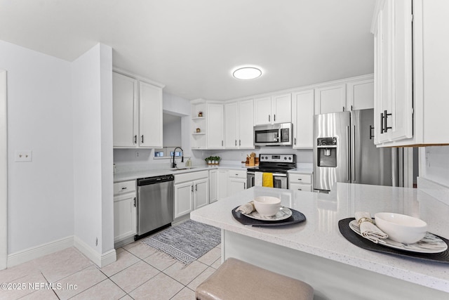 kitchen with appliances with stainless steel finishes, kitchen peninsula, sink, and white cabinets