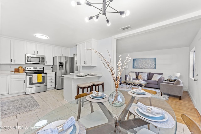 kitchen featuring an inviting chandelier, stainless steel appliances, light tile patterned floors, and white cabinets