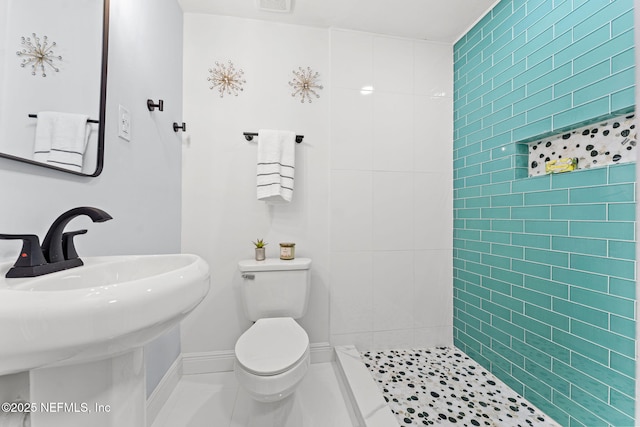 bathroom featuring sink, tiled shower, tile patterned floors, and toilet