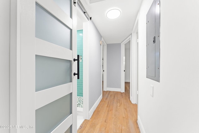 hallway with light hardwood / wood-style flooring, electric panel, and a barn door