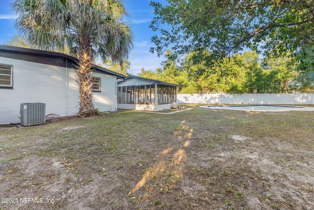 view of yard featuring a fenced in pool, central AC unit, and a sunroom