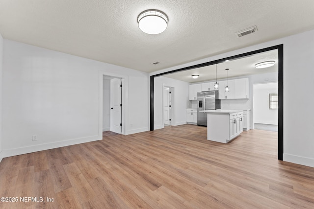 kitchen with light hardwood / wood-style flooring, stainless steel fridge, hanging light fixtures, a center island, and white cabinets