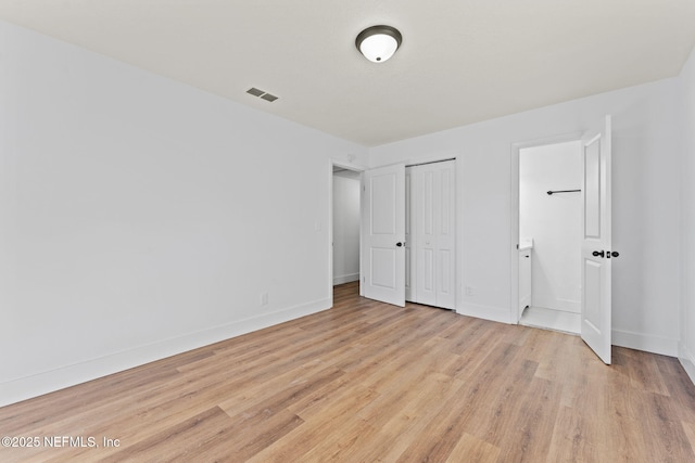 unfurnished bedroom with connected bathroom, light hardwood / wood-style floors, and a closet