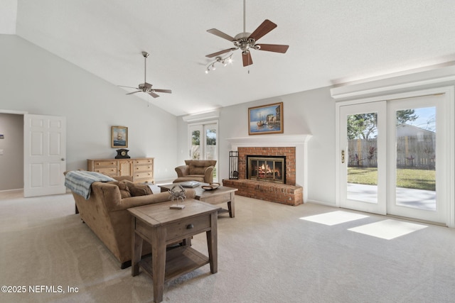 carpeted living room with french doors, high vaulted ceiling, a brick fireplace, and ceiling fan