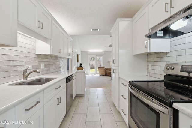 kitchen featuring appliances with stainless steel finishes, a textured ceiling, white cabinets, decorative backsplash, and sink