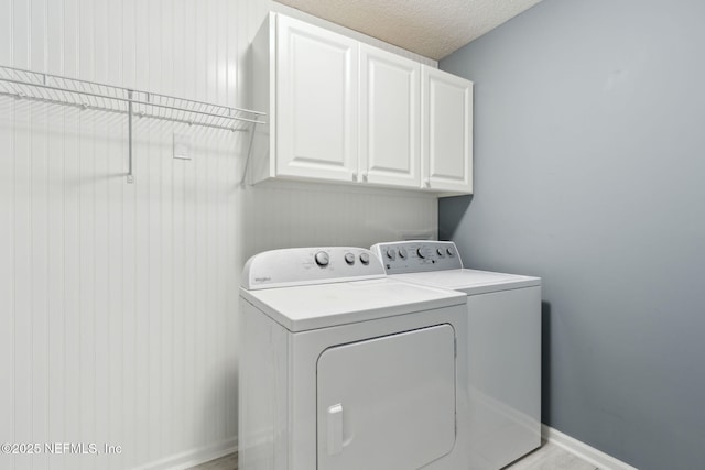 washroom with cabinets, a textured ceiling, and washing machine and clothes dryer