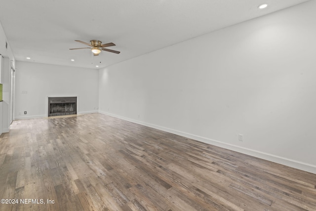 unfurnished living room featuring recessed lighting, a fireplace, wood finished floors, and baseboards