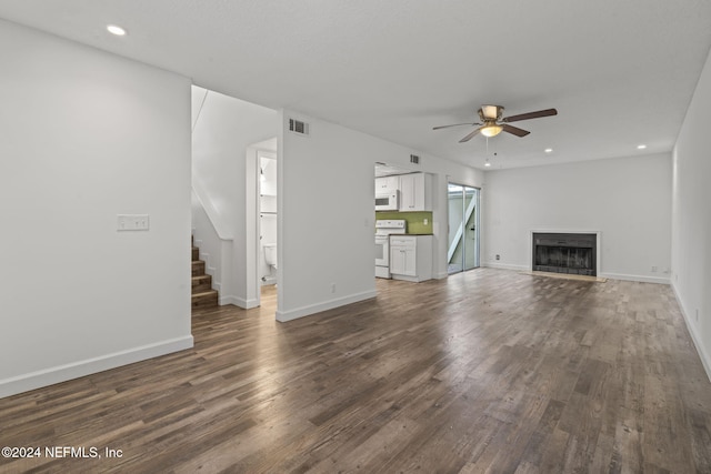 unfurnished living room with ceiling fan, dark wood-type flooring, stairs, a fireplace, and recessed lighting