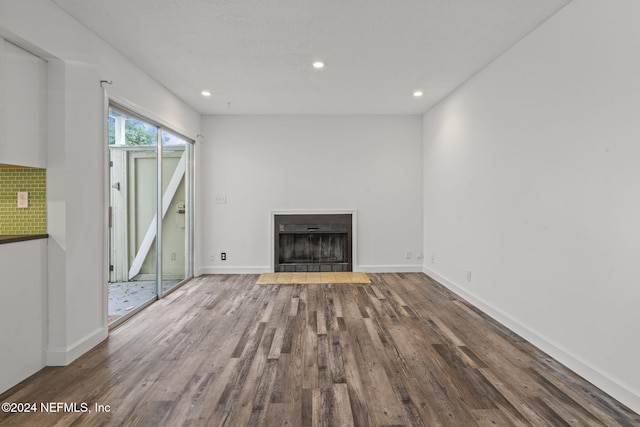 unfurnished living room with a fireplace with flush hearth, baseboards, wood finished floors, and recessed lighting