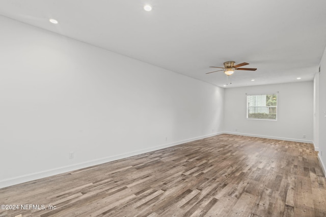 unfurnished room with baseboards, wood finished floors, and recessed lighting