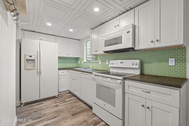 kitchen with an ornate ceiling, dark countertops, white appliances, and backsplash