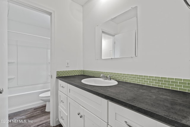 full bathroom featuring decorative backsplash, toilet, vanity, wood finished floors, and  shower combination