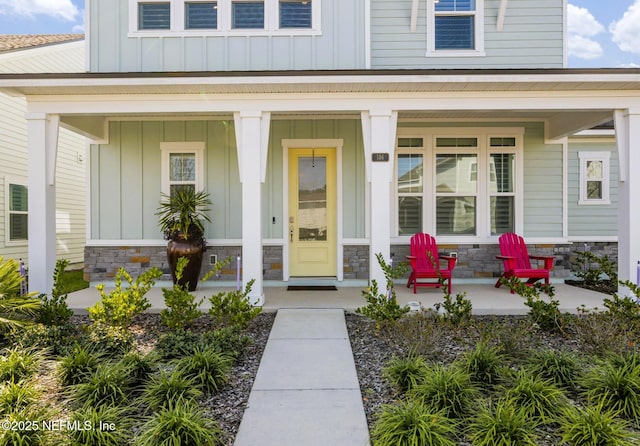 entrance to property featuring board and batten siding, stone siding, and a porch