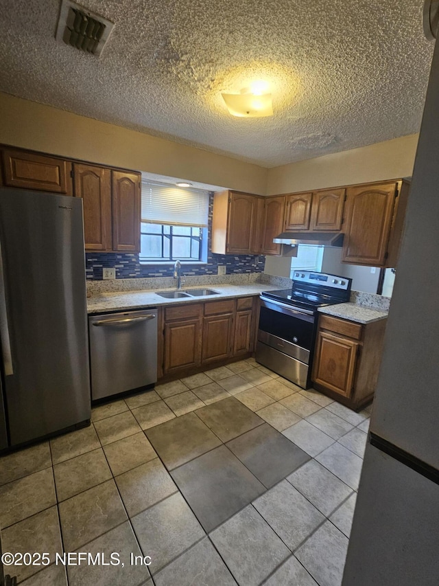 kitchen featuring sink, light tile patterned floors, a textured ceiling, and appliances with stainless steel finishes