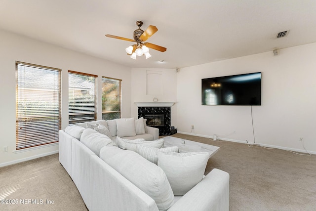 living room with a fireplace, light colored carpet, visible vents, a ceiling fan, and baseboards