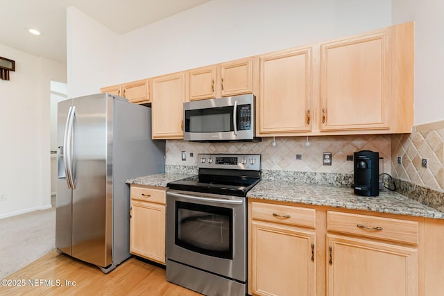 kitchen with tasteful backsplash, light stone counters, stainless steel appliances, and light brown cabinetry