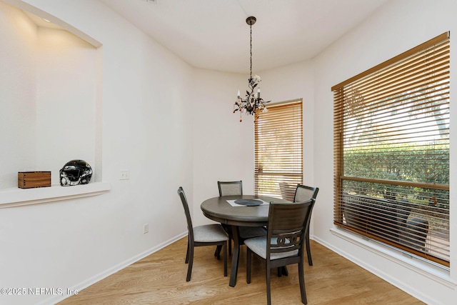 dining space with baseboards, light wood finished floors, and a notable chandelier