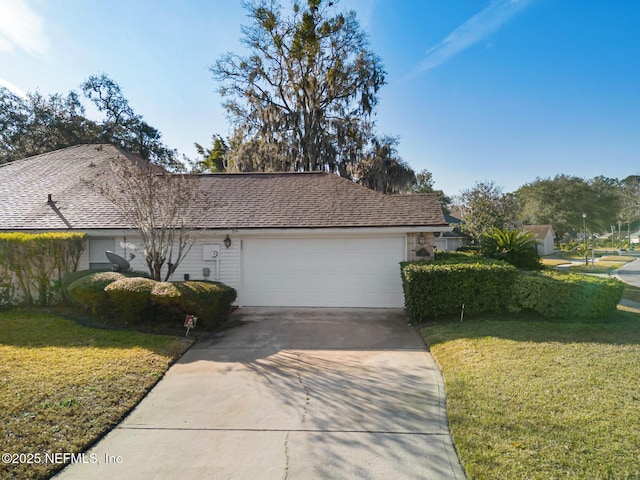 ranch-style home with a garage, a shingled roof, concrete driveway, and a front yard