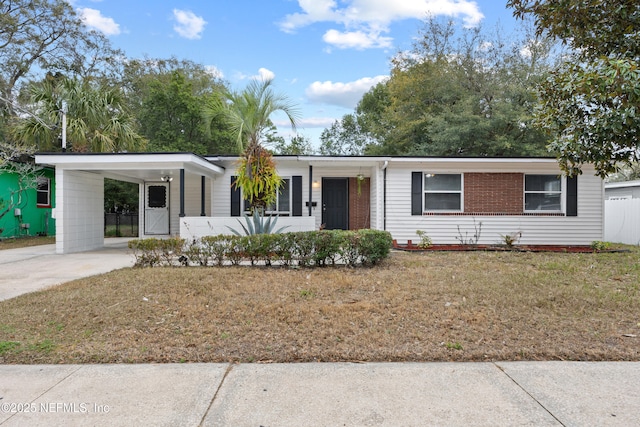 ranch-style house featuring concrete driveway, an attached carport, a front lawn, and brick siding