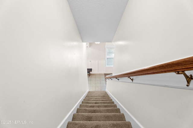 stairs featuring a textured ceiling and carpet flooring