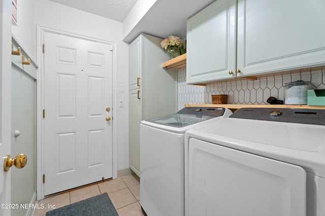 washroom featuring washing machine and dryer, cabinets, a textured ceiling, and light tile patterned flooring